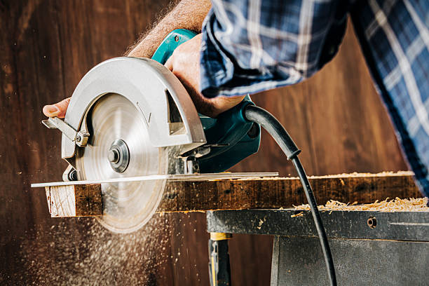 istock Male carpenter using electric circular saw in home workshop with wood chips flying. 2226702931