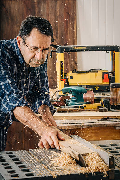 istock Male carpenter using electric circular saw in home workshop with wood chips flying 2226703005