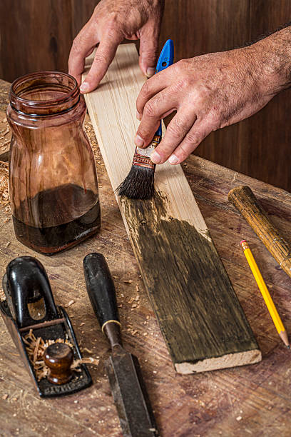istock Male carpenter stain dying lumber plank in home workshop 2226703139