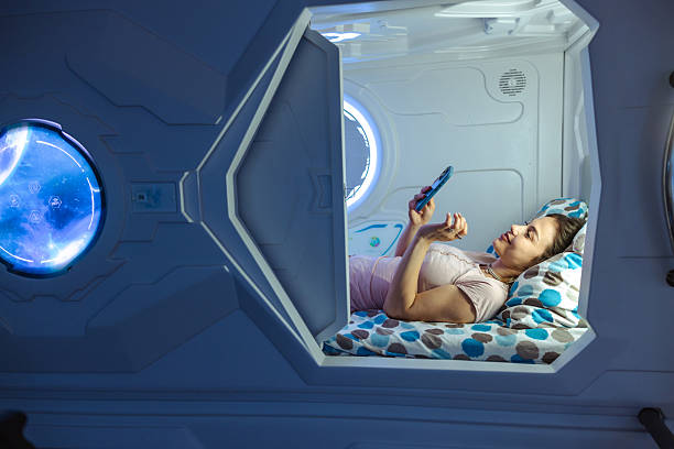 istock Young woman relaxing in a futuristic sleeping pod while using her smartphone 2226705067