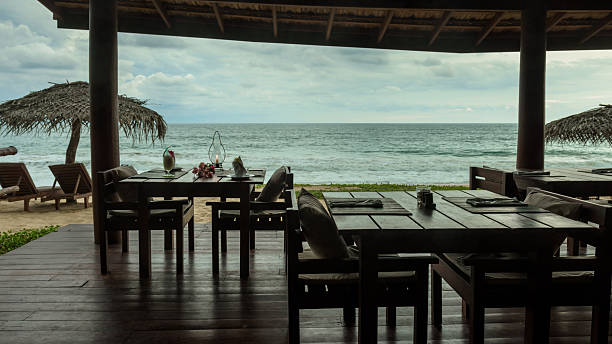 Oceanfront restaurant with empty tables overlooking tropical beach on cloudy day