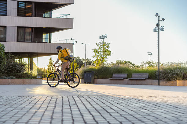 istock Courier on a bicycle delivering at sunset near a modern urban building 2226713207