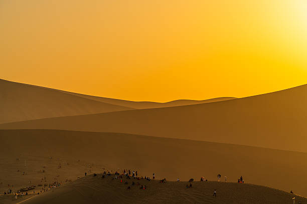 A large group of people are enjoying the sunset in the desert