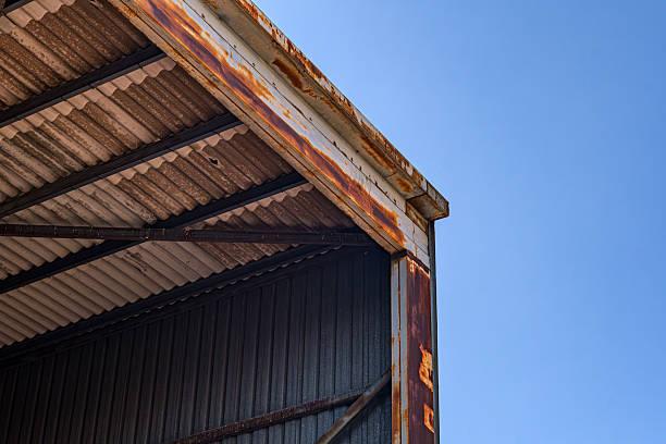 Rusty industrial warehouse roof against clear sky. Detailed view of a rusty warehouse roof structure with corrugated metal panels. Capturing the aged texture and industrial aesthetic.