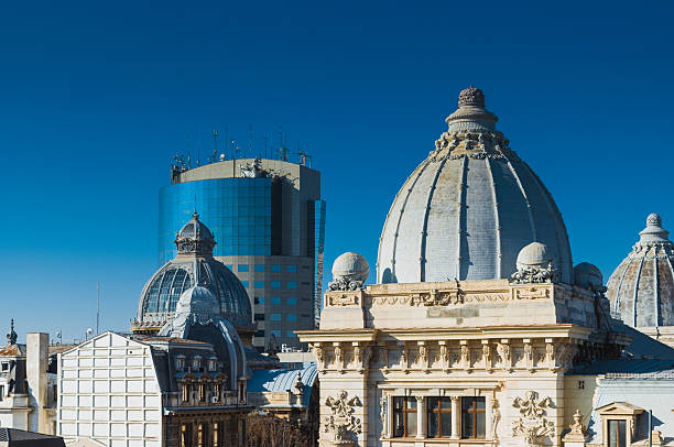 Classical and modern architecture merge in this cityscape, showcasing ornate historic domes alongside a sleek glass skyscraper under a clear blue sky. The juxtaposition highlights the blending of old and new in urban environments, offering a striking display of architectural evolution and creativity. Bathed in sunlight, the scene embodies the dynamic spirit of the metropolitan area.