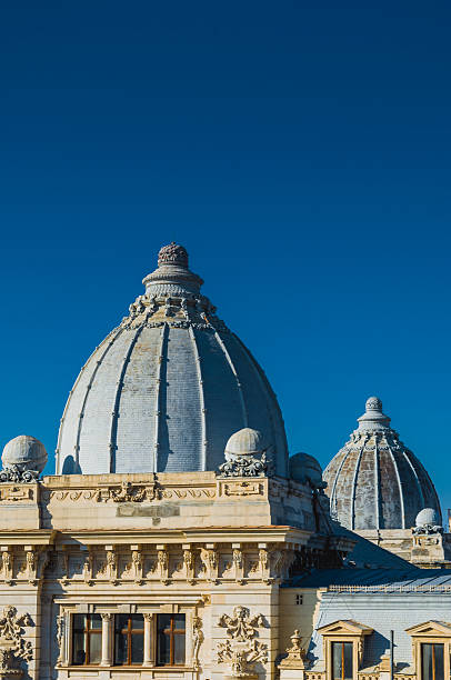 The image features the detailed architecture of building classic domes against a vibrant blue sky. The intricately designed structures showcase historic and artistic craftsmanship, capturing the essence of architectural beauty with their symmetrical form and decorative features.