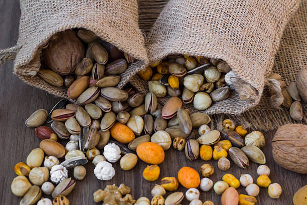 Various crispy nuts are poured from jute bags onto the table