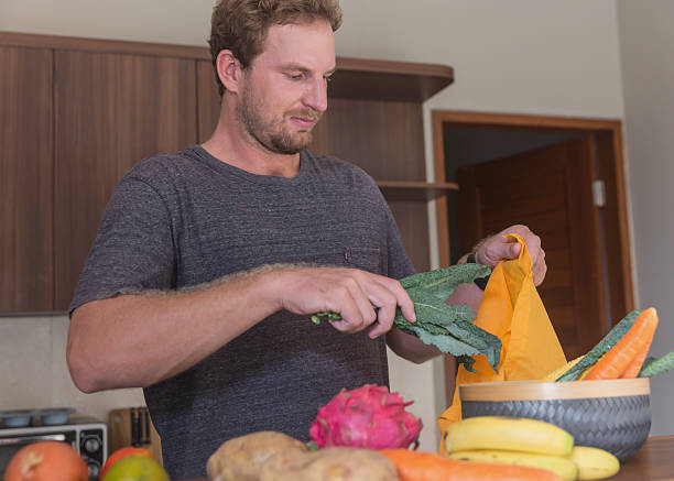 istock Caucasian Man Unpacking Fresh Produce from Grocery Bag 2226723552