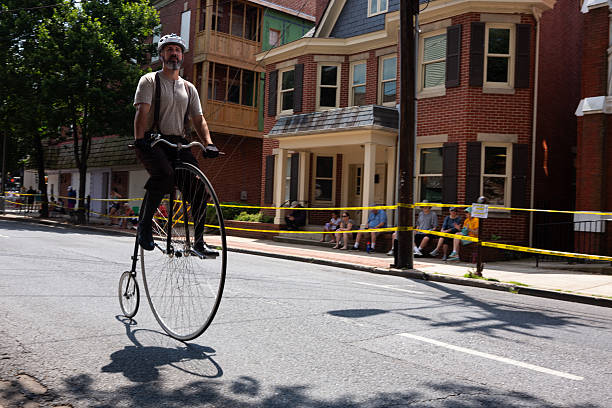 FREDERICK, MARYLAND, USA  JULY 12, 2025: Cyclists prepare for the National Clustered Spires High Wheel Race, the only event of its kind in the United States, by warming up and getting accustomed to their penny-farthing bicycles. Racers from around the world gather in downtown Frederick, where spectators line the barriers on a sunny summer day to watch participants speed through the streets in this unique and lively competition featuring vintage high-wheel bikes.