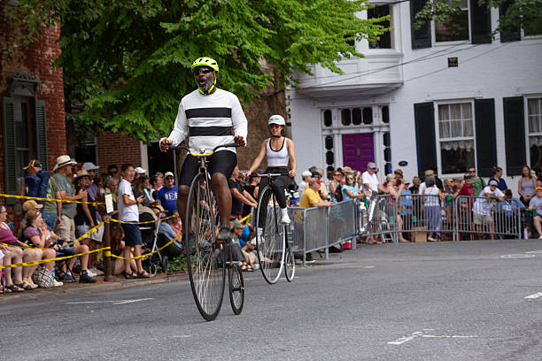 FREDERICK, MARYLAND, USA  JULY 12, 2025: Cyclists race penny-farthings in the National Clustered Spires High Wheel Race, the only event of its kind in the United States, drawing participants from around the world to speed through the streets of downtown Frederick. Spectators line the barriers on a sunny summer day in historic Frederick, cheering on riders as these vintage high-wheel bicyclesalso known as penny-farthingscompete in this unique and lively race.