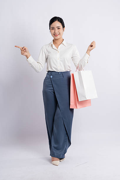 istock Woman with shopping bags points enjoying her purchases dressed elegantly against a plain background 2226733700