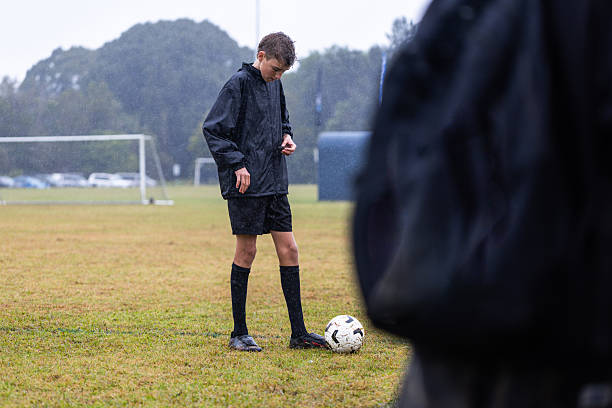 Australian teenage male soccer player takes a break from training  in the rain