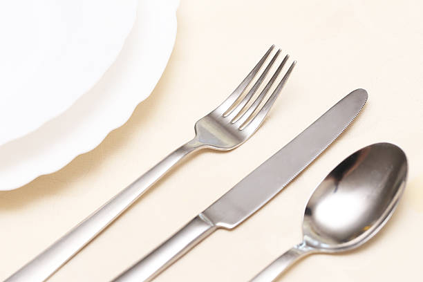 istock Elegant silver cutlery set. Fork knife spoon on cream tablecloth. White porcelain plate. Restaurant dining setup. 2226736738