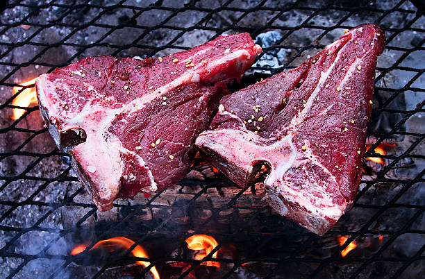 Grilling  beef steaks on flaming grill.