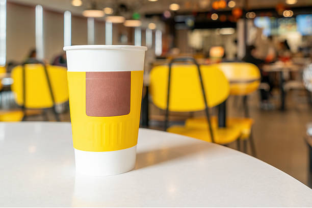 Paper cup with yellow and white design in a cafe setting