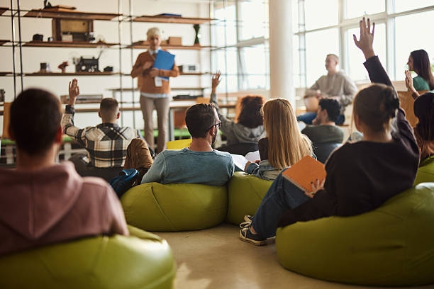 istock Rear view of students raising hands on a class at casual classroom. 2226743074