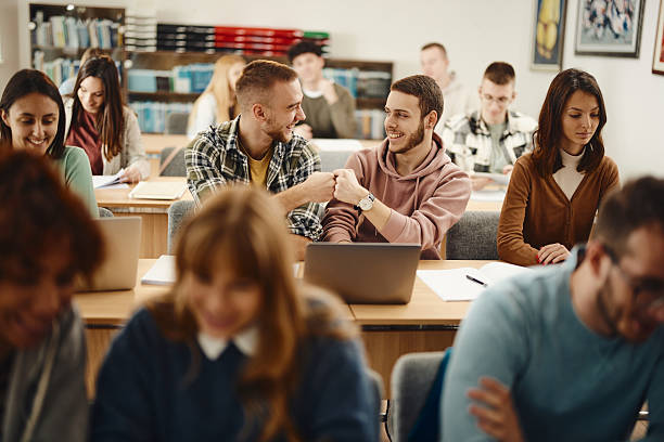 istock Happy college students fist bumping on a class at school. 2226743346