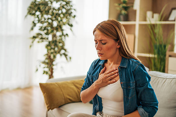 istock Woman suffering chest pain while sitting on sofa at home 2226750736