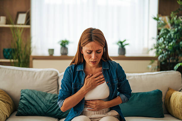 istock Woman suffering chest pain while sitting on sofa at home 2226750895