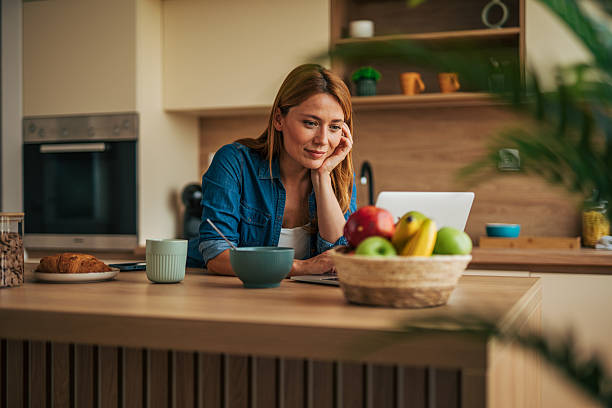 istock Woman working from home enjoying breakfast and using laptop in kitchen 2226751273