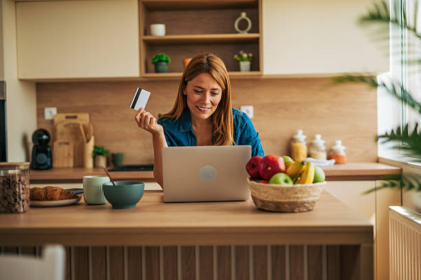 istock Woman making online purchases using laptop and credit card in kitchen 2226751662