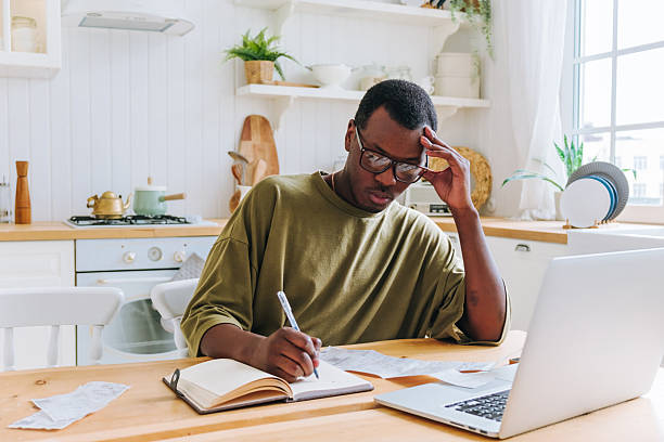 istock Stressed young man calculating domestic bills at home using laptop and notebook 2226751742