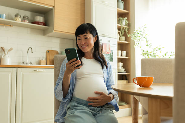 istock Japanese pregnant woman using mobile phone at kitchen 2226753058