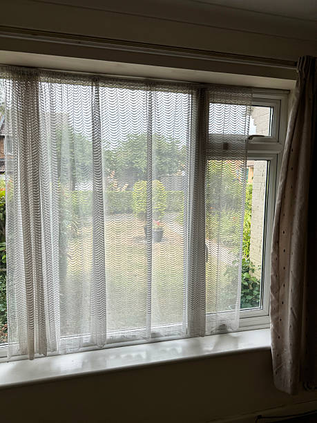 istock Image of double glazed window with net curtains providing privacy, partially obscuring the view of the front garden outside 2226754131