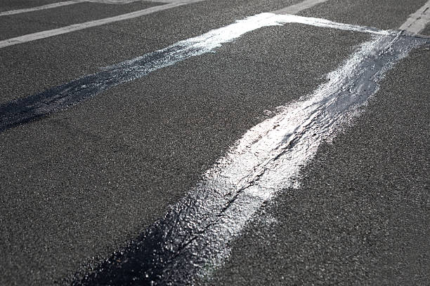 Luting lines stretch across a cracked, roof surface sealed with fresh, reflective tar. Contrast between textures hints at wear and repair, marking a utilitarian space of rooftop