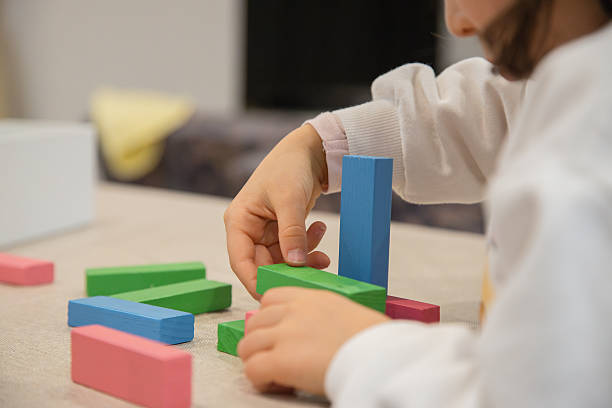 istock A young child plays indoors during the day, focusing intently while building a structure with colorful wooden blocks, developing fine motor skills, creativity, and early cognitive abilities. 2226755912
