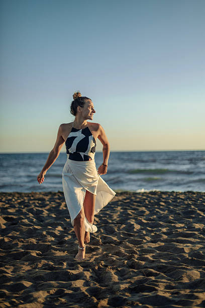 istock Confident Woman Walking Along the Beach at Sunset 2226756261
