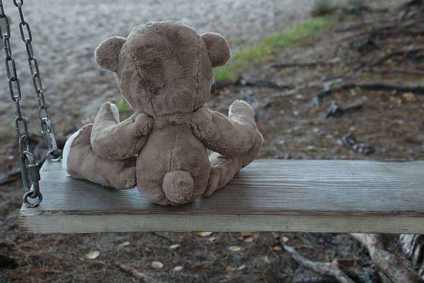 istock Lonely teddy bear on swing in park, back view 2226756329