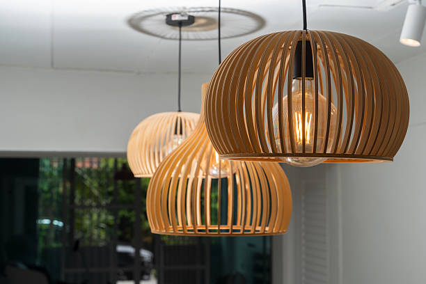 istock Modern wooden pendant lamps with glowing bulbs hanging from ceiling in interior space with natural warm lighting 2226756540