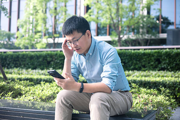 istock A tired Asian man using smartphone to communicate about business matters 2226756729