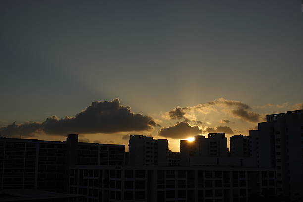 The sun sets above Singapore eastern housing residential building with beautiful crepuscular rays and cloud