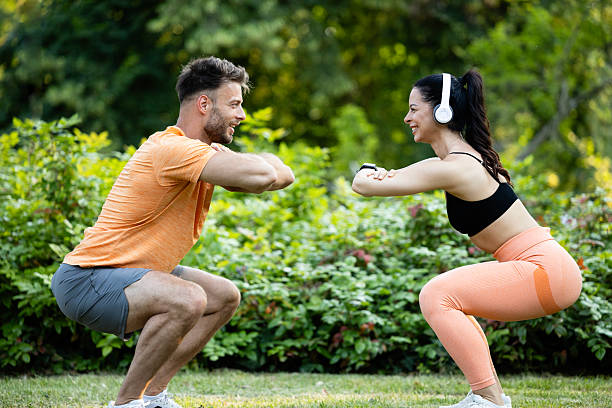Fitness people exercising and doing squats together in the park.