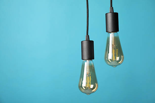 istock Light bulbs hanging on cords against light blue background, space for text 2226762111