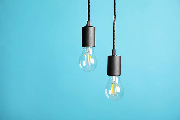istock Light bulbs hanging on cords against light blue background 2226762137