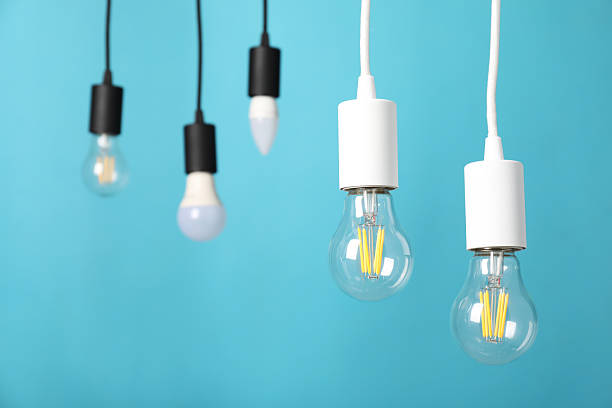 istock Light bulbs hanging on cords against light blue background 2226762149