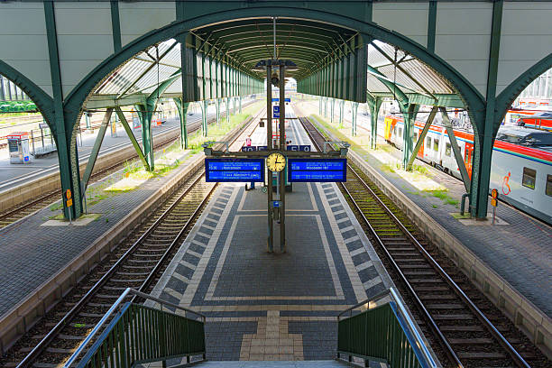 Darmstadt, Germany - June 16, 2025: Captivating view of Darmstadt train station featuring modern architecture, tracks, platforms, and digital clock under sunlight.