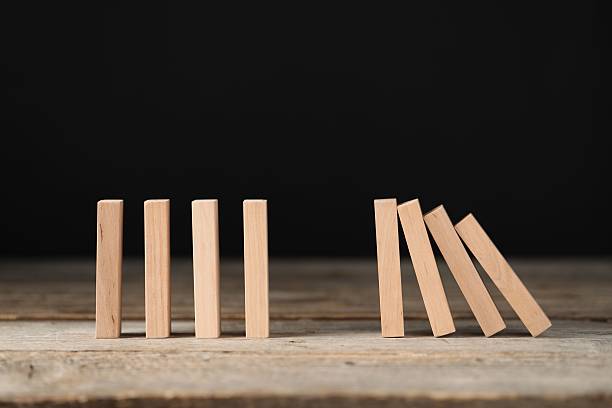 istock Domino effect. Wooden blocks falling on table against black background 2226763071