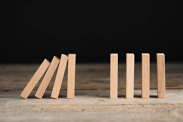 istock Domino effect. Wooden blocks falling on table against black background 2226763079