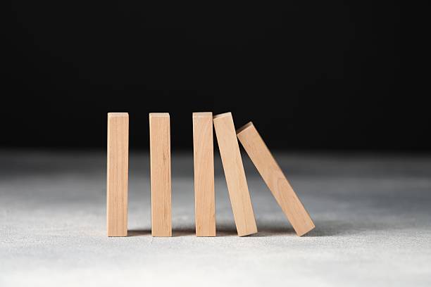 istock Domino effect. Wooden blocks falling on light table against black background, closeup 2226763090