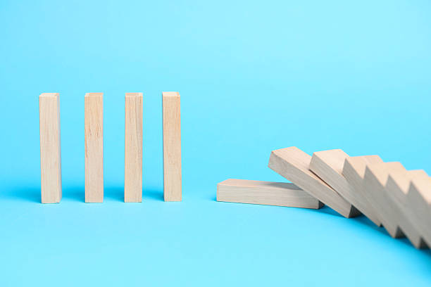 istock Domino effect. Wooden blocks falling on light blue background 2226763118