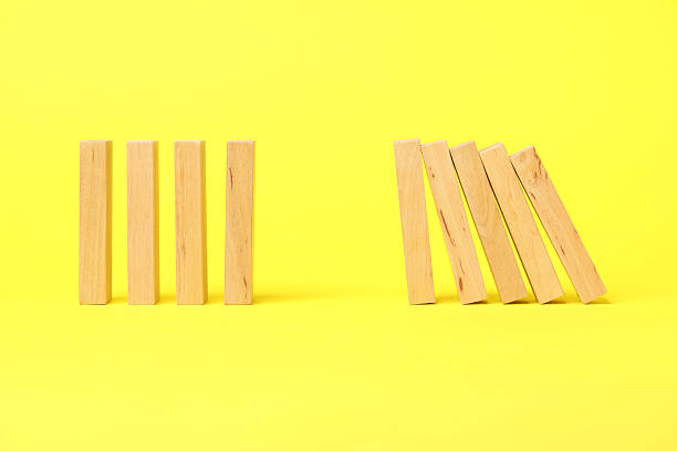 istock Domino effect. Wooden blocks falling on yellow background 2226763129