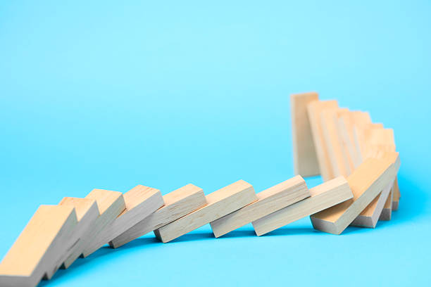 istock Domino effect. Wooden blocks falling on light blue background 2226763199