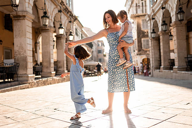 istock Mother Holding Hands with Daughters as They Dance Through City 2226763519