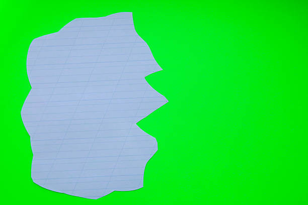 An irregularly torn sheet of checkered paper is placed on a bright green background. This composition can symbolize unspoken ideas,