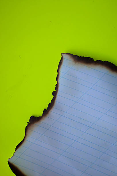 istock A sheet of checkered paper with burnt edges is placed on a bright lemon background. This visualization can symbolize the end of something, destruction of information, 2226763706