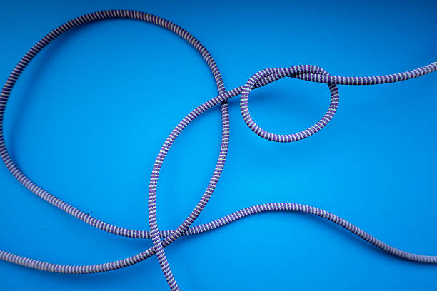 A gray-blue cord with white stripes is intricately tangled on a rich blue background. This textured composition evokes associations with climbing, adventure, or technical tasks, suitable for illustrations on the theme of challenges and solutions.